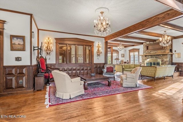 living room with a stone fireplace, beamed ceiling, a textured ceiling, and light wood-type flooring