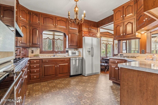 kitchen with tasteful backsplash, stainless steel appliances, sink, a notable chandelier, and hanging light fixtures