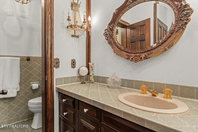 bathroom featuring tile patterned flooring, vanity, toilet, and tile walls