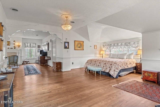 bedroom featuring hardwood / wood-style floors, a textured ceiling, and lofted ceiling