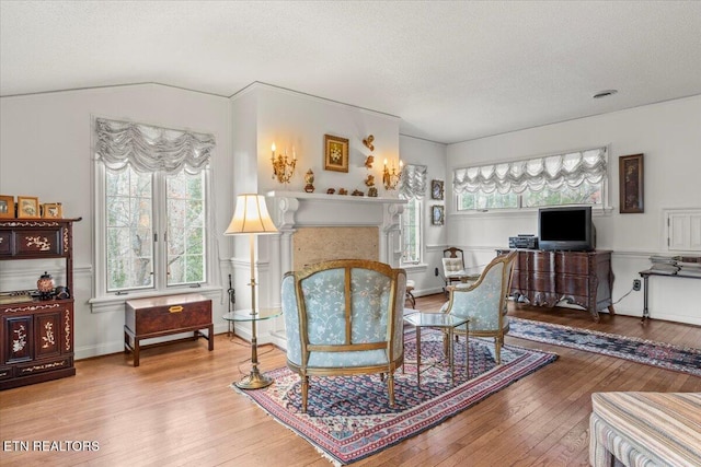 living area featuring a textured ceiling, hardwood / wood-style flooring, and vaulted ceiling