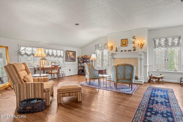 living area featuring a textured ceiling, hardwood / wood-style flooring, and lofted ceiling