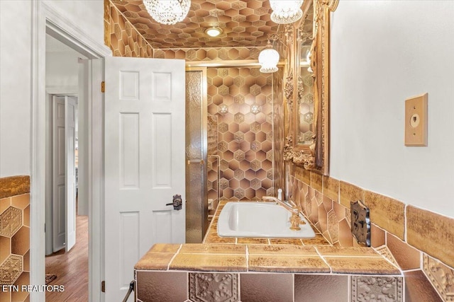 bathroom with hardwood / wood-style floors, a notable chandelier, sink, and a tub