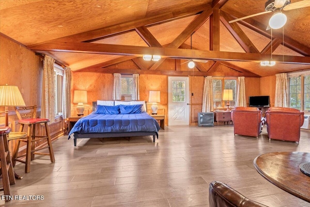 bedroom with ceiling fan, wooden walls, lofted ceiling with beams, and hardwood / wood-style flooring