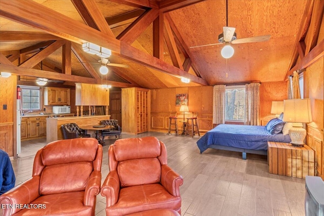 bedroom with beamed ceiling, wood walls, light wood-type flooring, and high vaulted ceiling