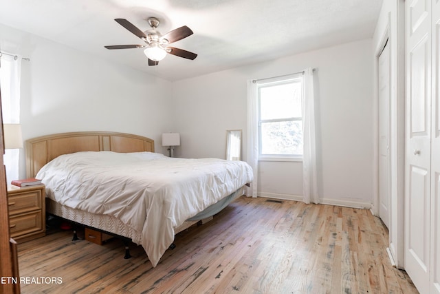 bedroom with a closet, light hardwood / wood-style floors, and ceiling fan