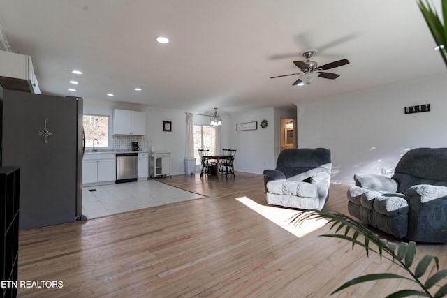 living room with ceiling fan, sink, light hardwood / wood-style floors, and plenty of natural light