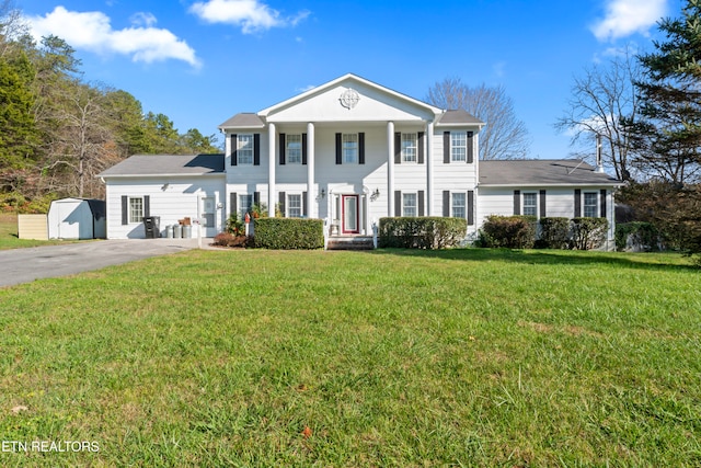 neoclassical / greek revival house with a front lawn and a storage shed