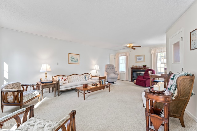 living room featuring ceiling fan, carpet floors, and a textured ceiling