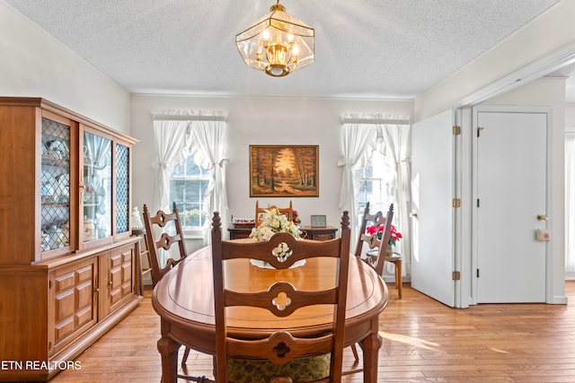 dining room with a chandelier, a textured ceiling, and light hardwood / wood-style flooring