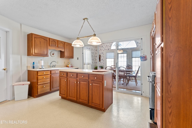 kitchen featuring pendant lighting, backsplash, a textured ceiling, and a kitchen island