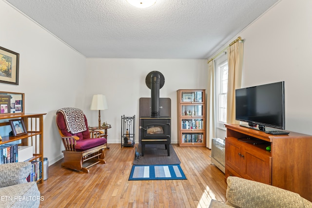 interior space with a textured ceiling, light wood-type flooring, and a wood stove