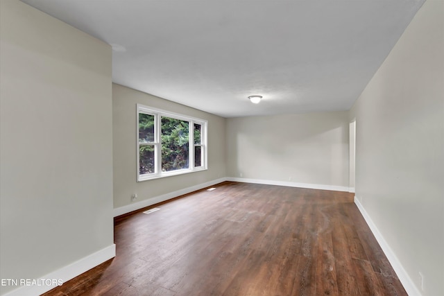 unfurnished room with dark hardwood / wood-style flooring