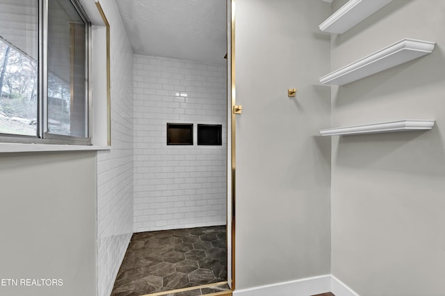 bathroom with a tile shower and a textured ceiling