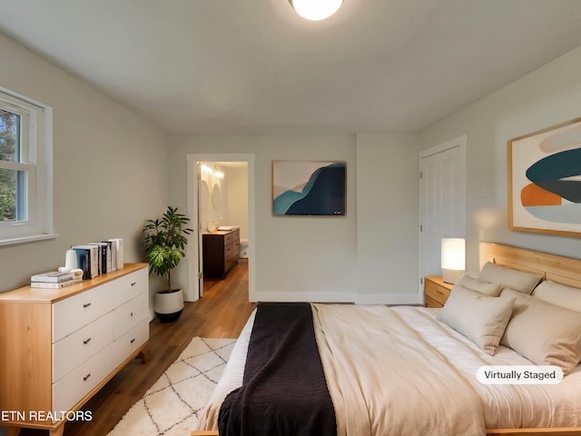 bedroom featuring ensuite bath and hardwood / wood-style floors