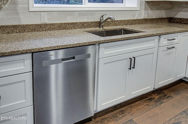 kitchen featuring light stone countertops, stainless steel dishwasher, dark hardwood / wood-style floors, white cabinetry, and sink