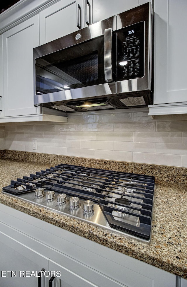 room details with white cabinets, appliances with stainless steel finishes, and backsplash