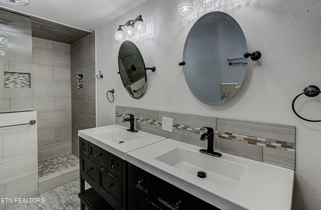 bathroom with tiled shower, vanity, and tasteful backsplash