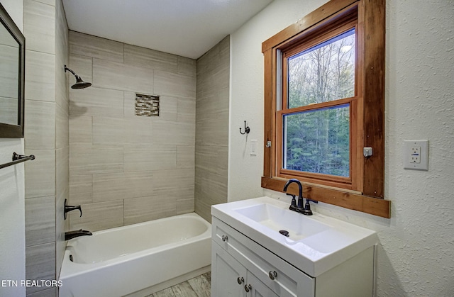 bathroom featuring vanity and tiled shower / bath