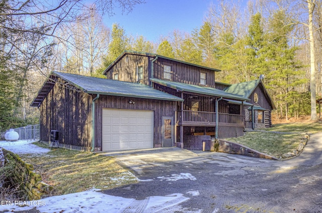 view of front facade with covered porch, a yard, and a garage