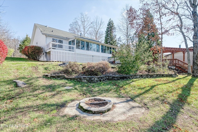 view of yard featuring a wooden deck, a sunroom, and an outdoor fire pit