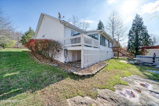 view of side of property with a sunroom, a yard, a hot tub, and a deck