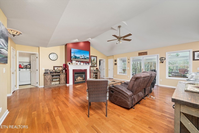 living room with hardwood / wood-style flooring, ceiling fan, washer / clothes dryer, and vaulted ceiling