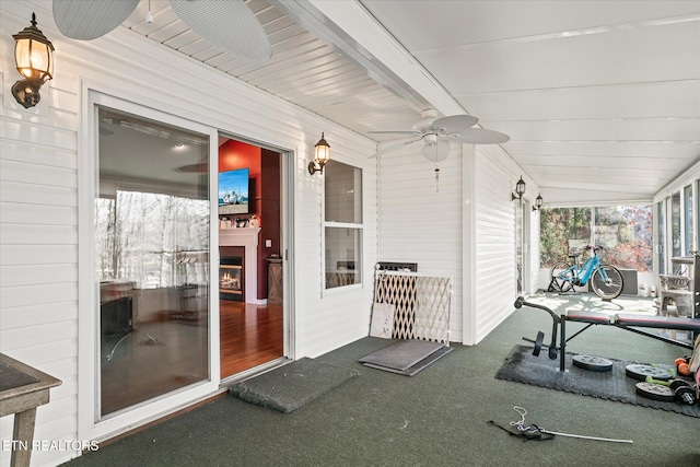 unfurnished sunroom featuring beam ceiling, exterior fireplace, and ceiling fan