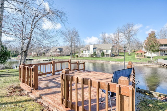 dock area featuring a gazebo, a water view, and a lawn