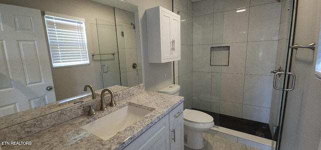 bathroom featuring a shower with door, vanity, and toilet