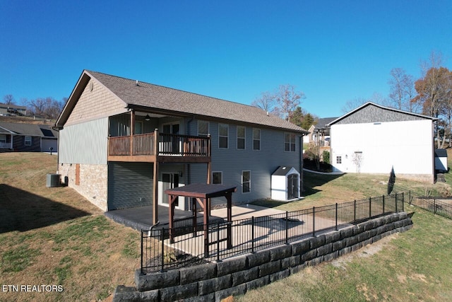 rear view of house with a balcony, a storage unit, a lawn, and a patio area