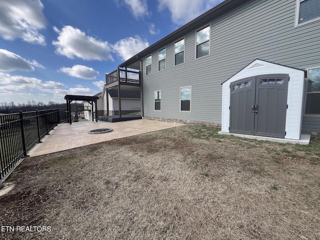 back of house with a fire pit, a patio, and a storage unit