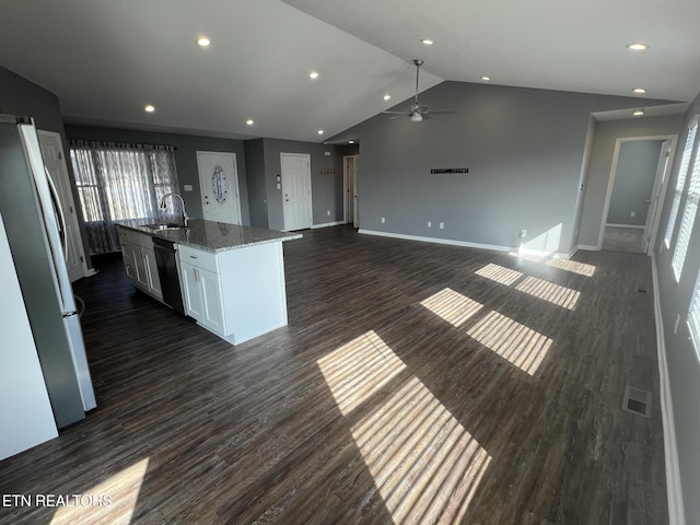 kitchen with refrigerator, sink, white cabinets, light stone counters, and a center island with sink