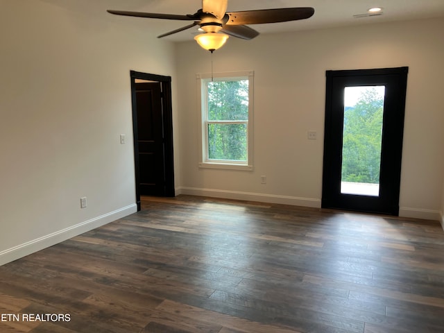 unfurnished room with a wealth of natural light, dark wood-type flooring, and ceiling fan