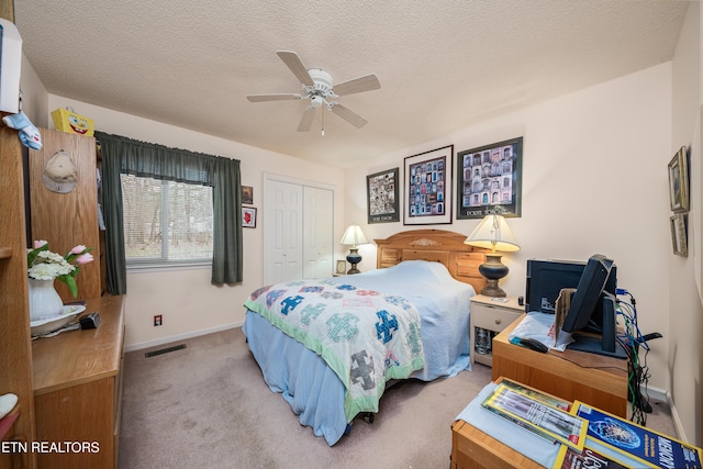 bedroom featuring light carpet, a textured ceiling, a closet, and ceiling fan