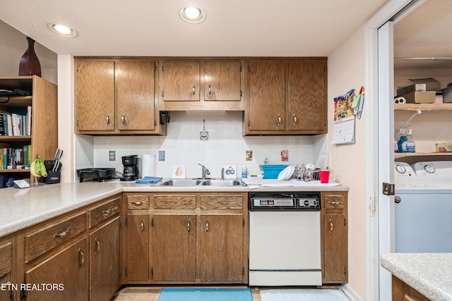 kitchen with separate washer and dryer, decorative backsplash, white dishwasher, and sink