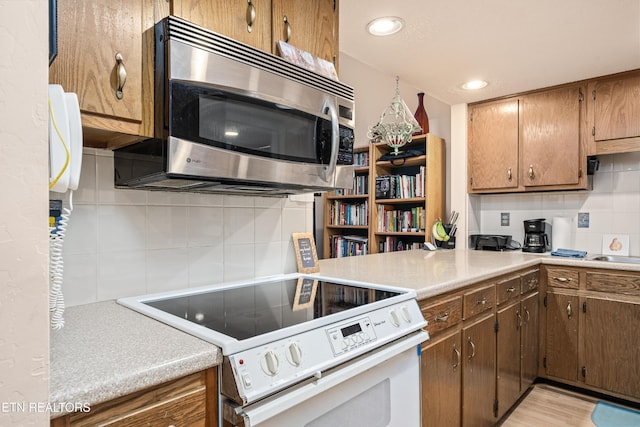 kitchen featuring electric stove, decorative backsplash, and light wood-type flooring