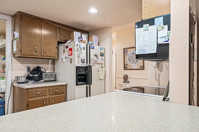 kitchen with a textured ceiling and white refrigerator with ice dispenser