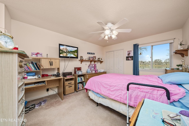 carpeted bedroom with a textured ceiling, a closet, vaulted ceiling, and ceiling fan