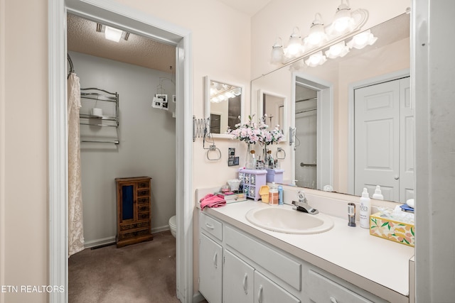 bathroom featuring vanity, a textured ceiling, and toilet