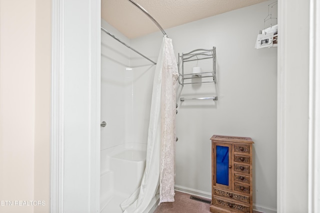 bathroom with curtained shower and a textured ceiling