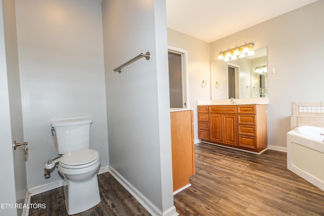 bathroom featuring a washtub, vanity, hardwood / wood-style flooring, and toilet