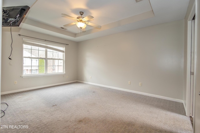 carpeted empty room featuring a tray ceiling and ceiling fan