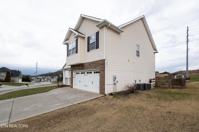 view of side of home featuring central AC, a yard, and a garage