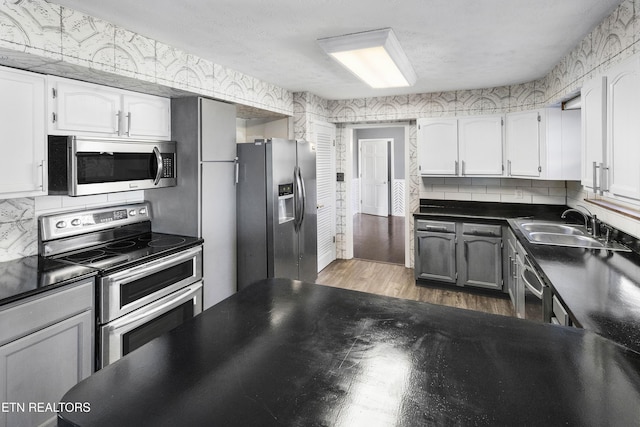 kitchen with dark wood-type flooring, white cabinets, sink, decorative backsplash, and appliances with stainless steel finishes