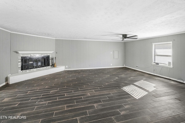 unfurnished living room with a textured ceiling, dark hardwood / wood-style flooring, ceiling fan, and ornamental molding