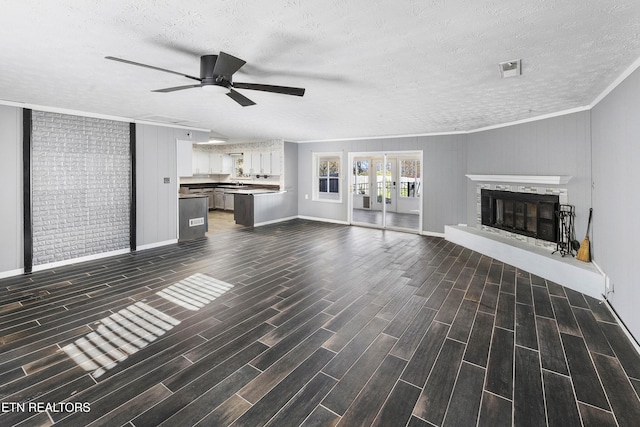 unfurnished living room featuring ceiling fan, dark hardwood / wood-style flooring, crown molding, and a textured ceiling