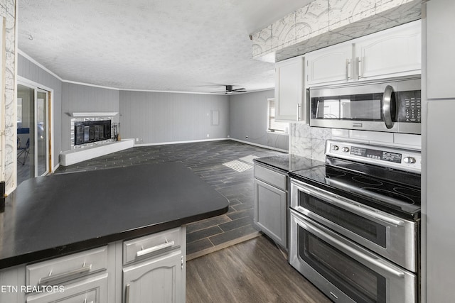 kitchen featuring appliances with stainless steel finishes, dark hardwood / wood-style flooring, ornamental molding, ceiling fan, and white cabinets