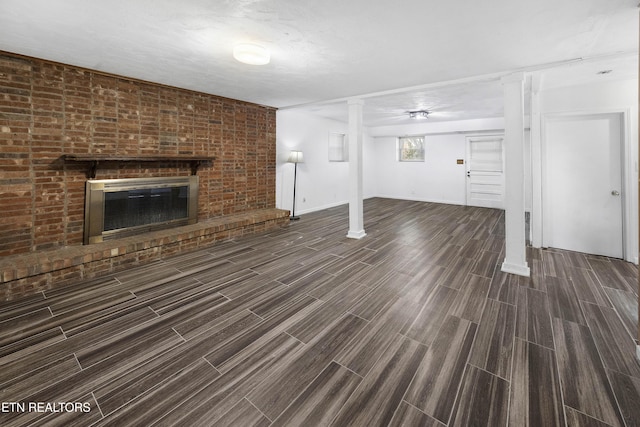 unfurnished living room with a textured ceiling, dark hardwood / wood-style floors, a fireplace, and brick wall