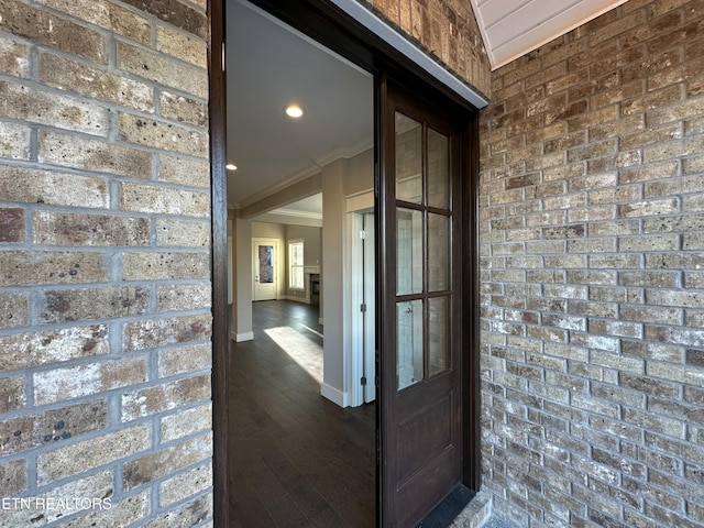 corridor featuring dark hardwood / wood-style floors, crown molding, and brick wall